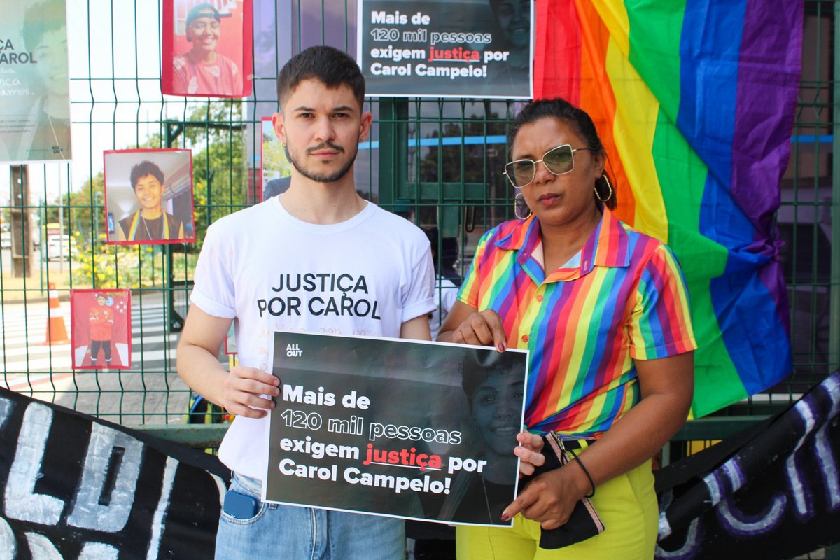 The image shows Marcos Melo, LGBT+ activist from All Out, and Carol Campelo's mother holding a sign that reads: Over 120,000 people demand justice for Carol Campelo!