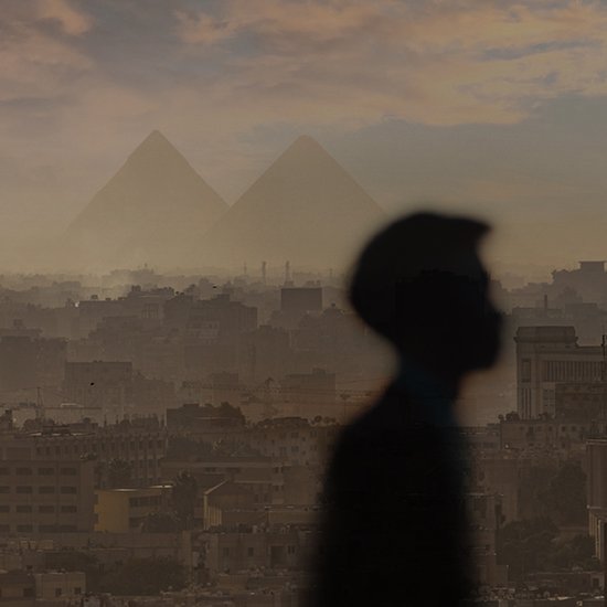 The image shows the figure of a person set against a backdrop of the pyramids of Giza.